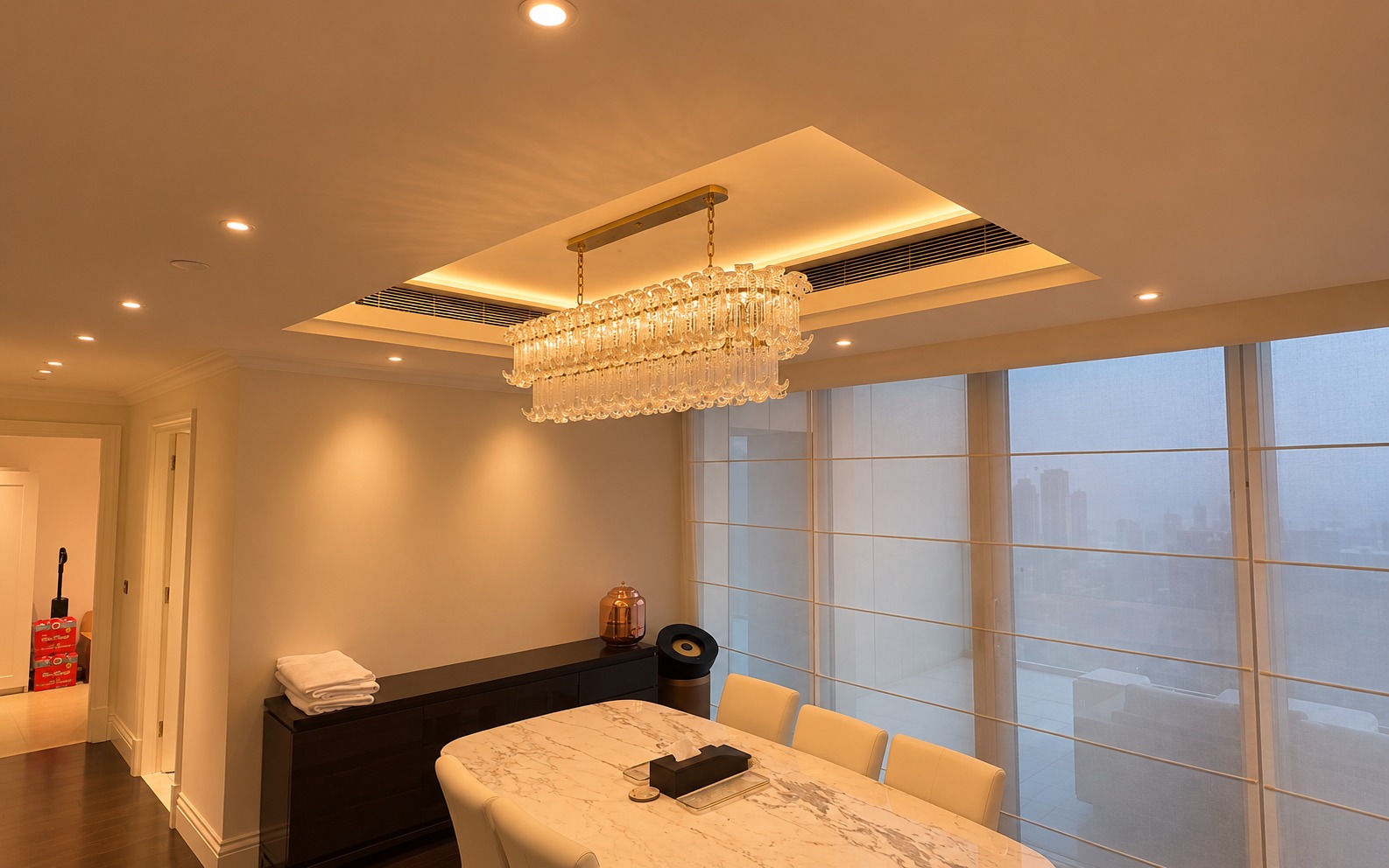 Living room at Kempinski The Boulevard Dubai with warm cove lighting and the Downtown skyline at sunset